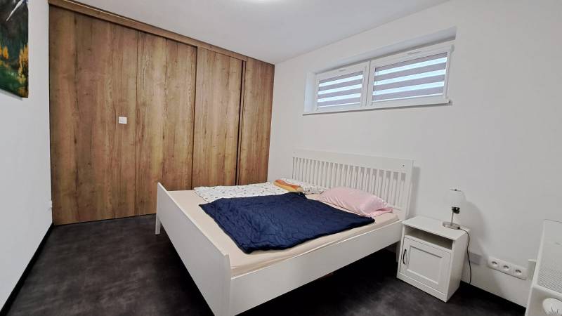 A bedroom with a white bed and a large wardrobe with a wooden decor in a 2-room apartment.