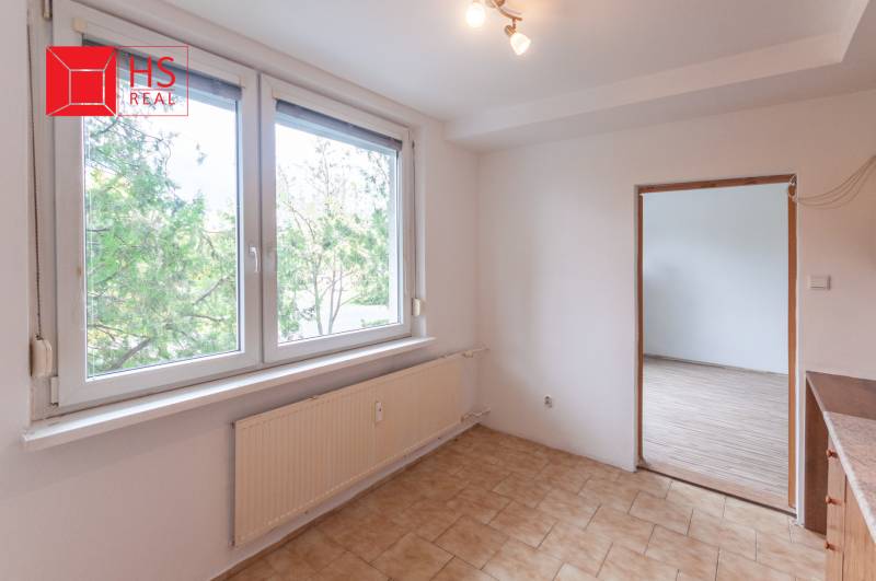 A room with a large window, tiles, and a wooden decor floor in a 3-room apartment.