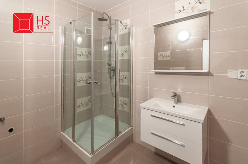 Bathroom with a shower in a 3-room apartment, light tiles, mirror above the sink.