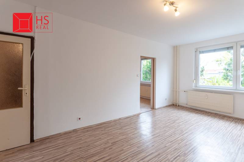 A spacious room with a wooden decor floor in a 3-room apartment.