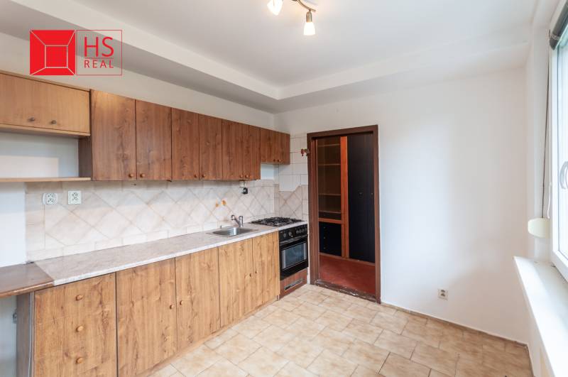 A kitchen in a 3-room apartment with wooden cabinets and tiles, floor with a pattern.