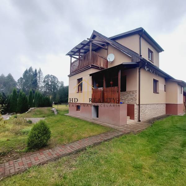 A family house in Liptovská Porúbka with a terrace, lawn, and trees on the property.