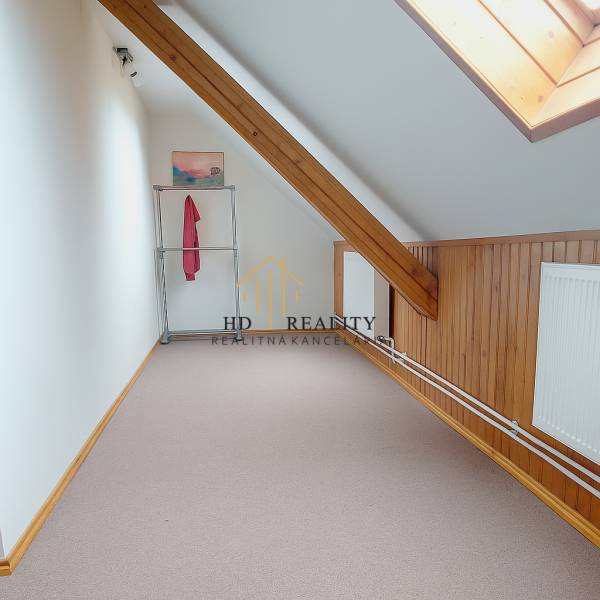 A hallway in the attic with wooden paneling, a radiator, and a coat rack in a family house.