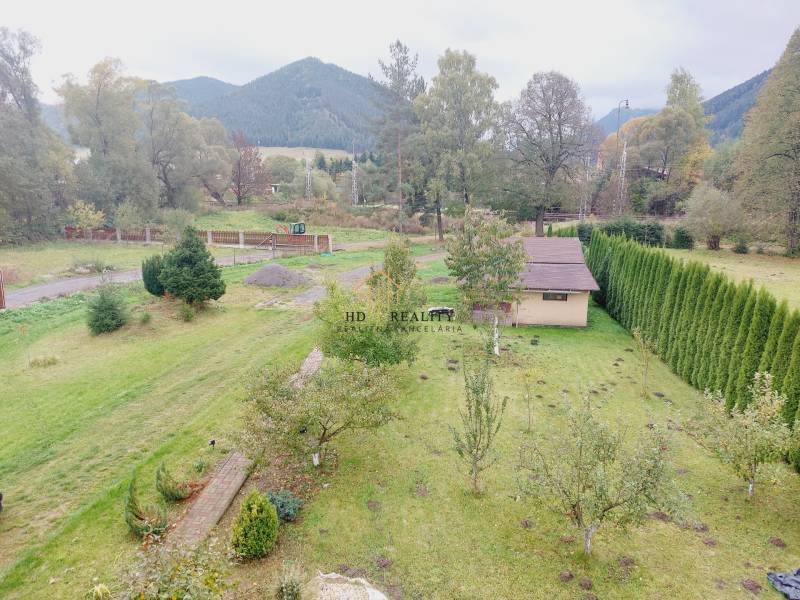 The garden of a family house in Liptovská Porúbka with a gazebo, trees, and a view of the hills.