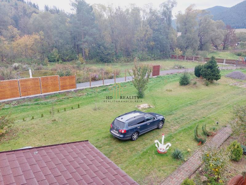 In Liptovská Porúbka, a family house with a lawn, a car, and the surrounding green landscape.