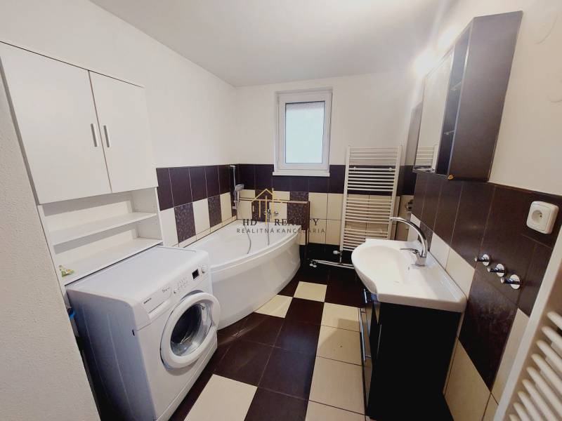 Bathroom in a family house with a washing machine, corner bathtub, and sink.