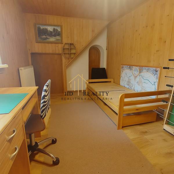 Interior of a family house with wooden decor, furniture, bed, and work desk.