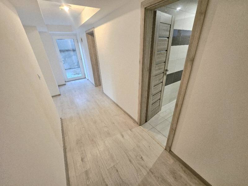 A hallway in a 3-room apartment with a wooden decor floor and a door to the bathroom.