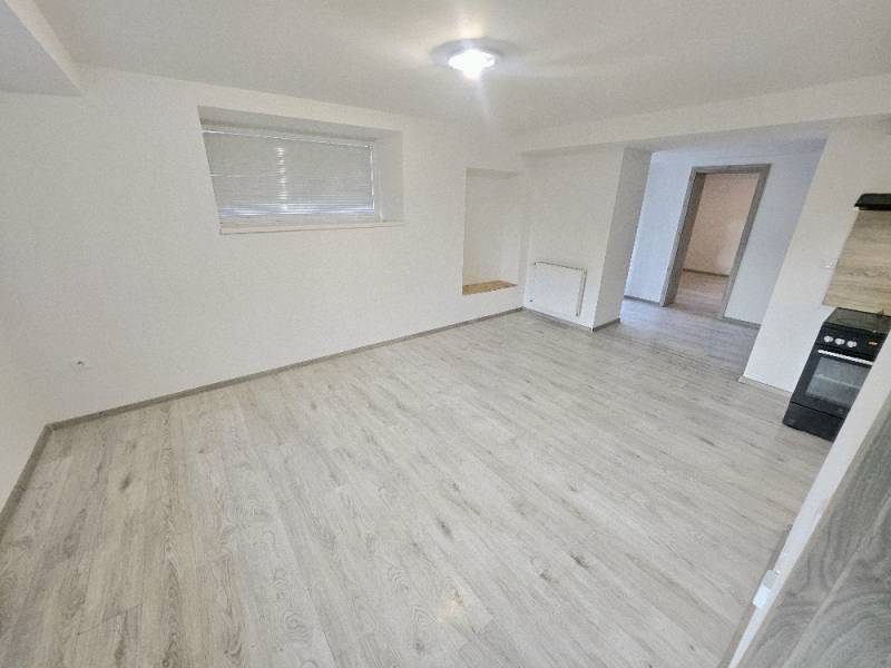 Living room of a three-room apartment with a wooden decor floor and an electric stove.