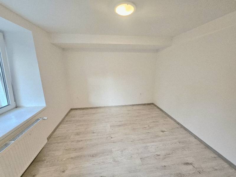 A room in a 3-room apartment with a wooden decor floor and white walls.