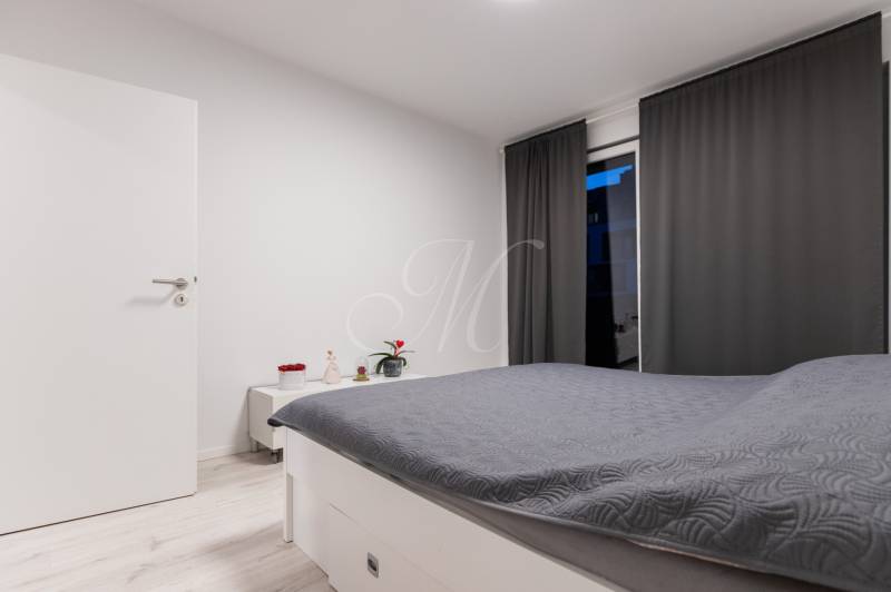 A bedroom with white furniture, gray curtains, and a bed in a two-room apartment.