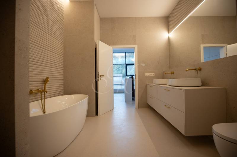 A bathroom with a freestanding bathtub, gold details, and a double sink in a 4-room apartment.