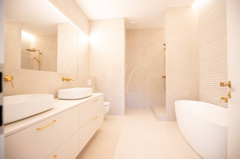 A spacious bathroom with golden elements, two sinks, and a freestanding bathtub in a 4-room apartment.