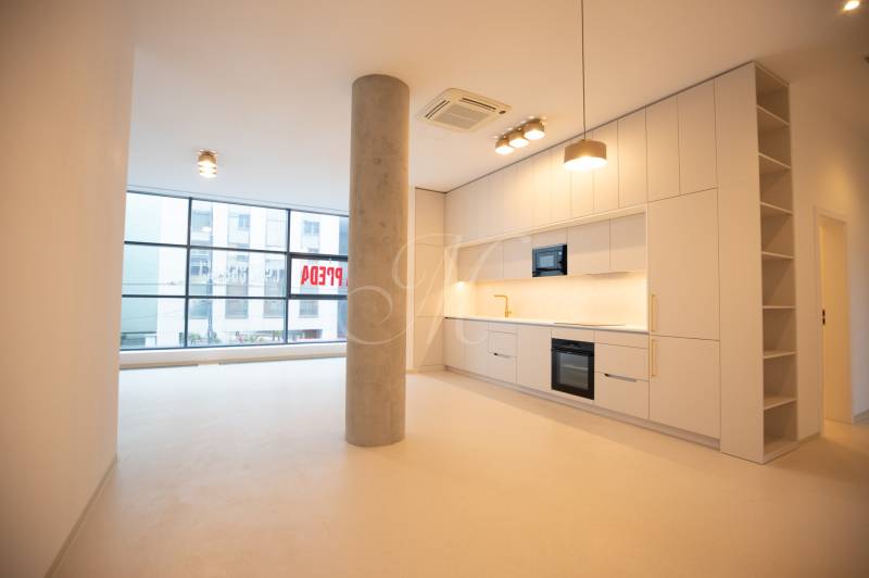 A kitchen in a 4-room apartment with white cabinets, a column, and large windows.