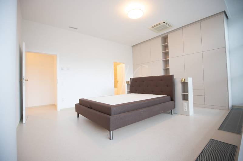 Bedroom of a 4-room apartment with a dark headboard and built-in wardrobes.