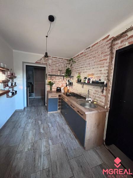 Kitchen in a 2-room apartment with brick walls and a floor with a wood decor.