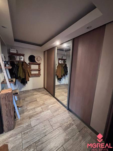 A hallway with a wooden decor floor, a built-in wardrobe, and a coat rack in a 2-room apartment.