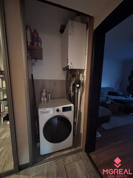Washing machine and boiler located in the storage space of a 2-room apartment with tiles.