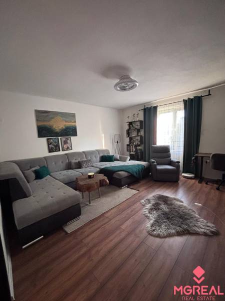 A living room with a comfortable sofa and a wooden decor floor in a two-room apartment.