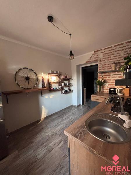 A kitchen in a 2-room apartment with a gray floor and brick cladding.