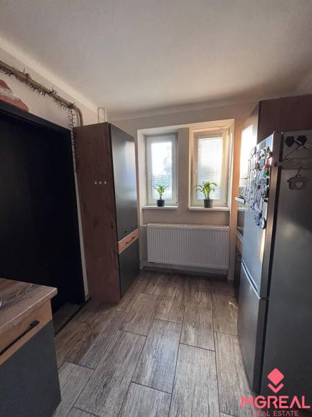 A kitchen in a 2-room apartment with a wood-patterned floor and modern furnishings.