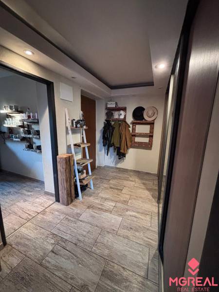 A hallway in a 2-room apartment with a coat rack, shelves, and tiles with a wooden design.