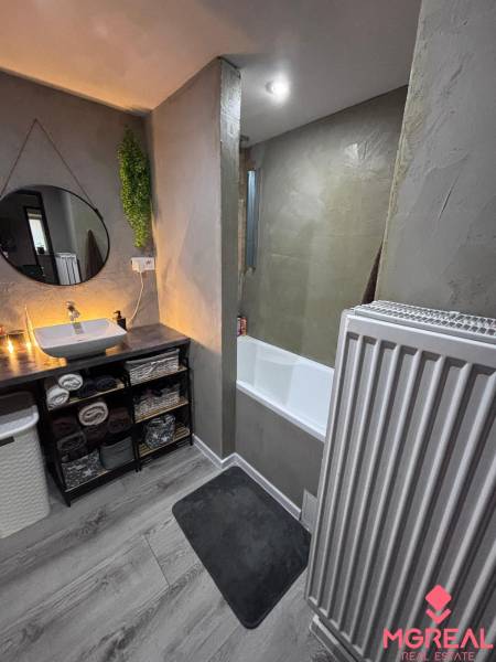 Bathroom in a 2-room apartment with a wooden decor floor and minimalist design.