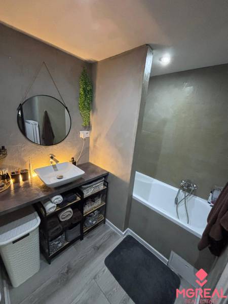 Bathroom in a 2-room apartment with a sink, bathtub, wooden decor flooring, and decorative elements.