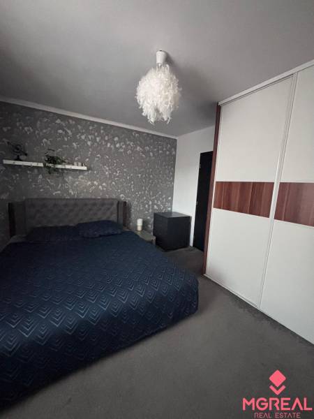 Bedroom in a 2-room apartment with a bed, wallpaper, and a wardrobe.