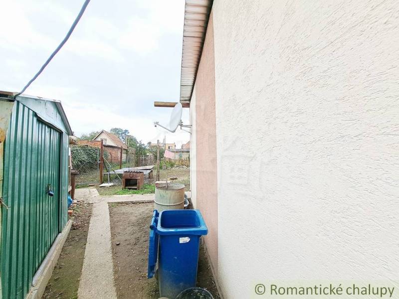 The courtyard of the family house in Ľudovítová with a metal shelter and a blue waste container.