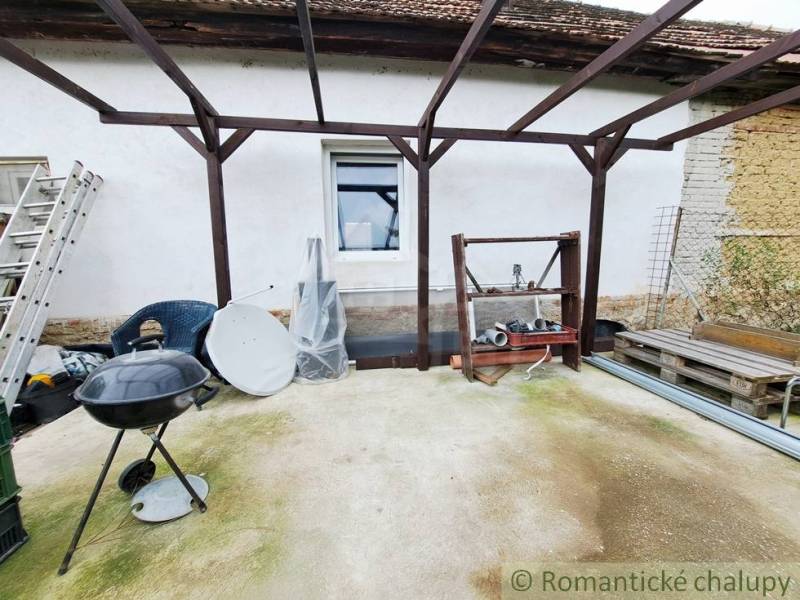 The garden of the family house in Ľudovítová with a pergola, grill, and building materials.