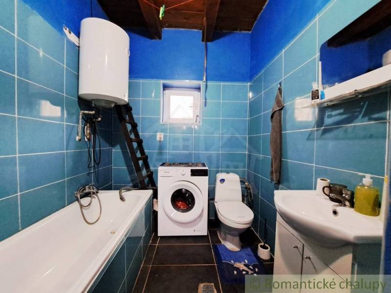 A bathroom in a family house with blue tiles, a bathtub, a sink, and a washing machine.