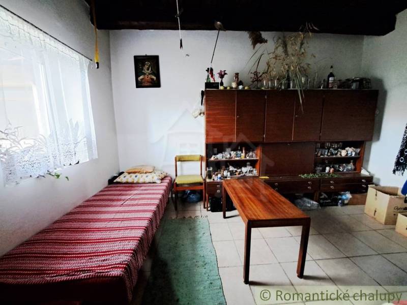 A simple room in a family house with a bed, carpets, and an open wardrobe.