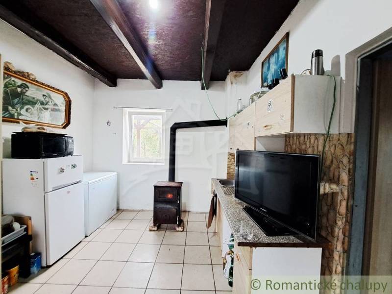 A kitchen in a family house with a stove, refrigerator, kitchen unit, and television.