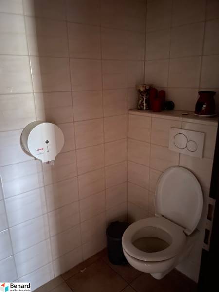 A restroom with tiles and a paper dispenser in commercial premises.