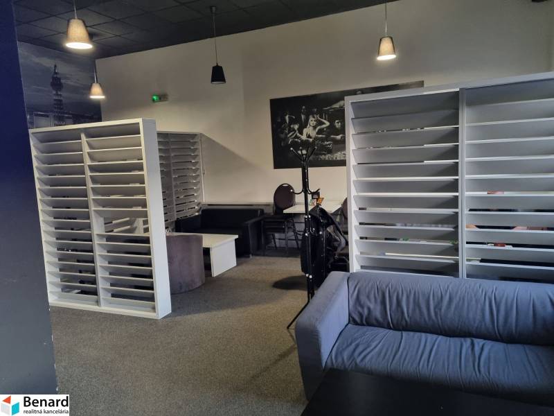 Commercial space with a sofa, white shelves, and carpeted flooring.