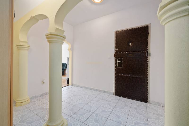 A hallway with ornamental tiles and columns in a 3-room apartment.