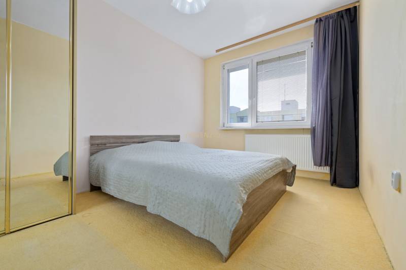 Bedroom in a 3-room apartment with a bed, mirrored wardrobe, and large window.