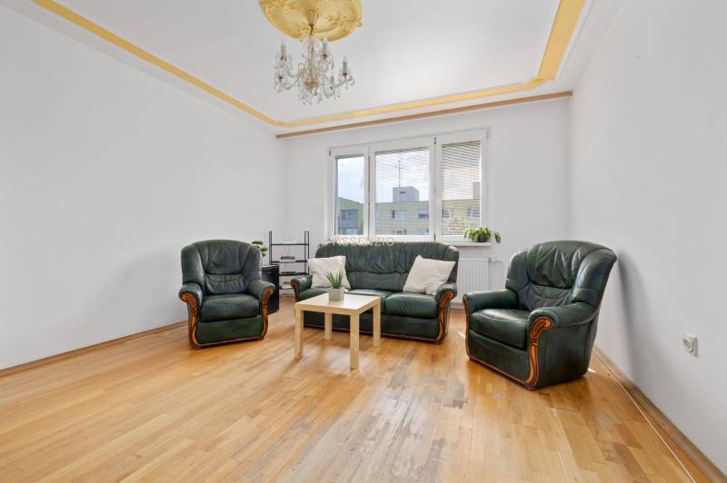 Living room with a leather sofa and armchairs, wooden floor, chandelier, 3-room apartment.