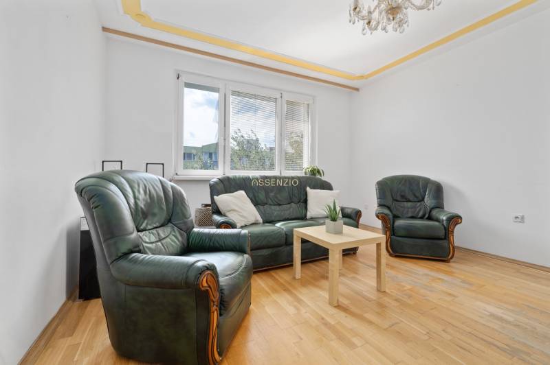 Living room in a 3-room apartment with a leather sofa set and a wooden table.