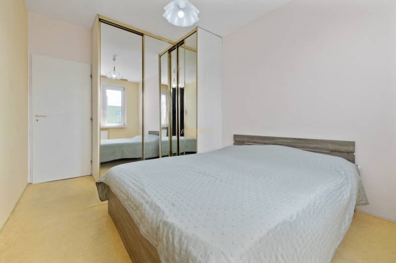 A bedroom with a mirrored wardrobe in a 3-room apartment has a bed and a window.