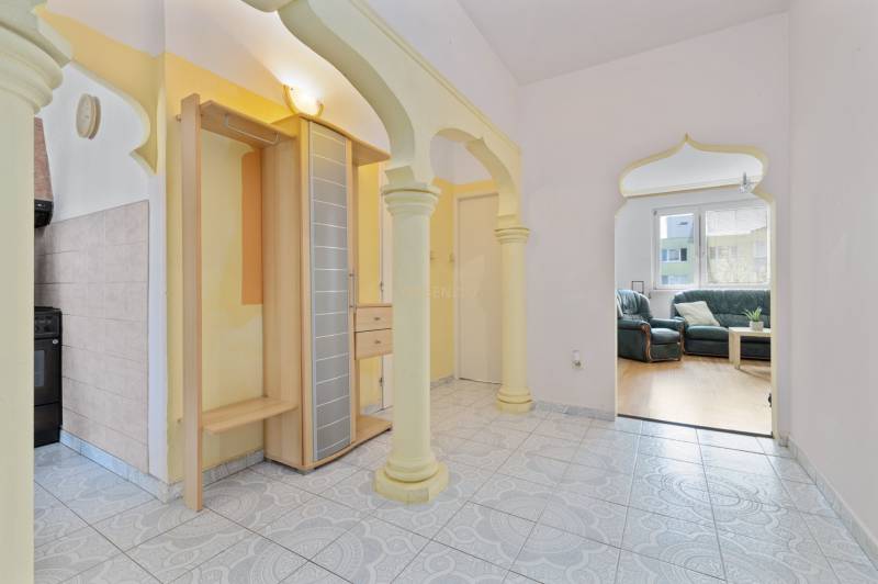 Interior of a 3-room apartment with arched doorways, tiled floor, and a view of the living room.