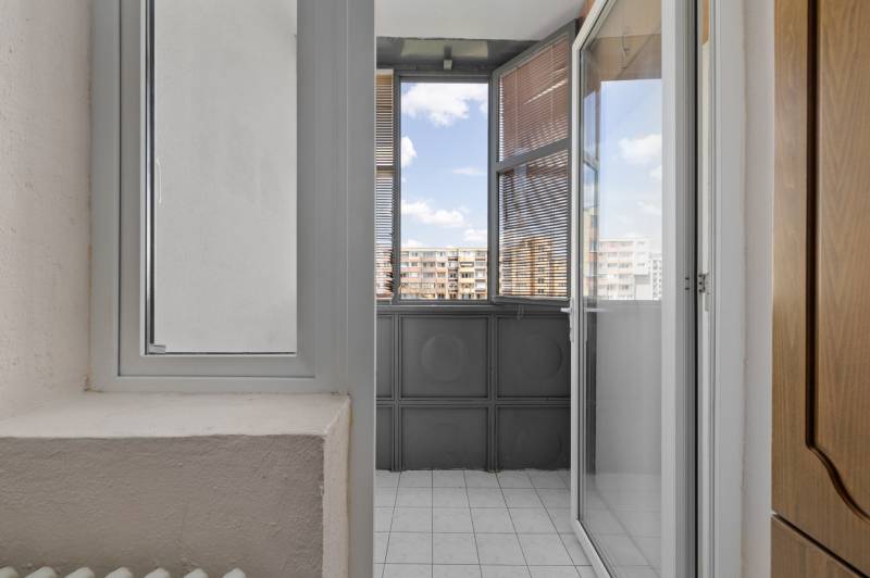 A balcony in a 3-room apartment with tiles and a view of the apartment blocks.