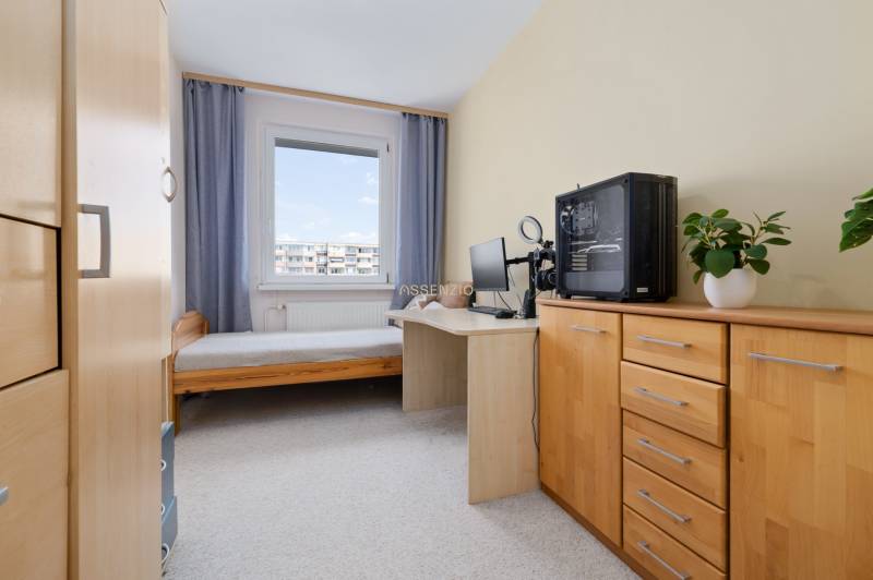 A children's room in a three-room apartment with wooden furniture, a small table, and a computer.