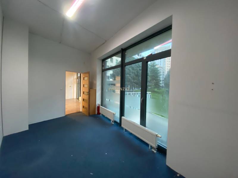 Interior of commercial spaces with large windows and wooden floor decor.