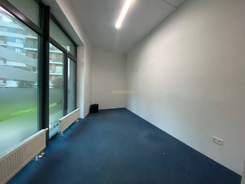 Commercial space with large windows and blue carpet, white wall.