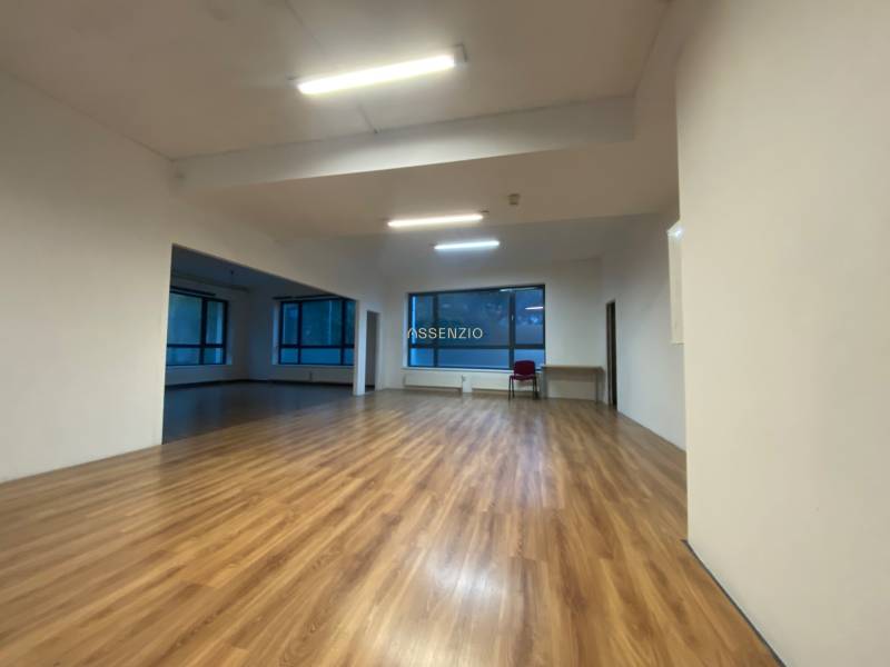 Commercial spaces with wood-patterned flooring and large windows.