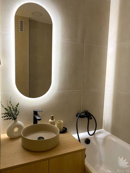 Elegant bathroom in a 4-room apartment with an illuminated mirror and stylish sink.