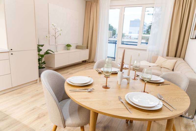 Dining table with a set of dishes, glasses, and a wooden decor floor in a 4-room apartment.