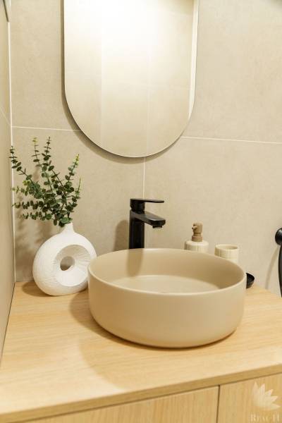 Bathroom in a 4-room apartment with a round sink, mirror, and decorative accessories.